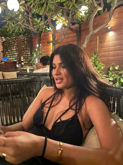 A candid shot from a night out with my friends. I'm wearing a black dress with a plunging neckline and strappy details, a bold and confident party look.