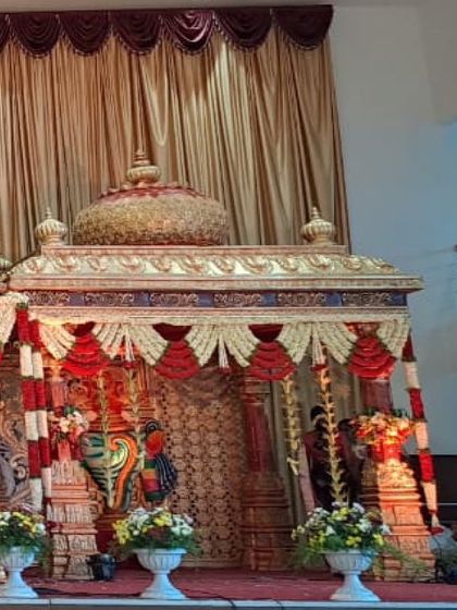 A side view of the magnificent temple-style wedding mantap. This angle reveals the depth and complexity of the structure, adorned with beautiful floral arrangements and traditional motifs.