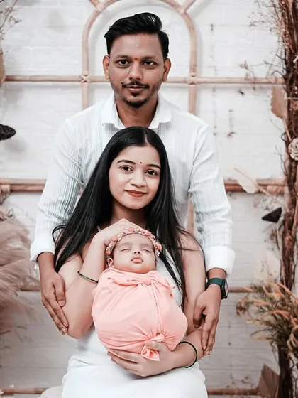 A lovely family portrait with their newborn daughter. The mother holds the baby while the father stands protectively behind them in our boho-chic studio setting.