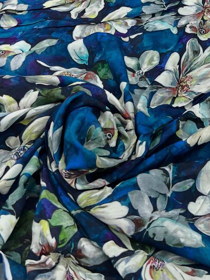 A deep blue printed muslin with a stunning, large-scale floral print. The fabric is soft, lightweight, and perfect for creating a dramatic and artistic outfit.