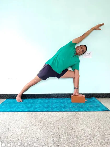 Utthita Parsvakonasana (Extended Side Angle Pose) with a block. The block brings the floor closer, allowing for full extension of the side body without collapsing the chest.