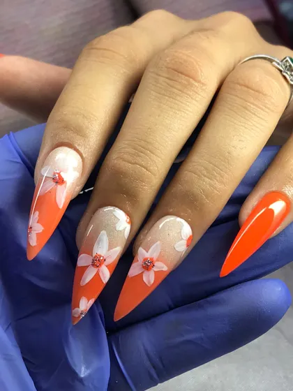 A beautiful example of client work. This set features a sharp stiletto shape with a vibrant orange and baby boomer ombre, adorned with delicate white flowers.