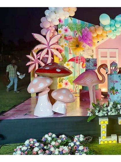A side view of the flamingo party stage, showing the layered props like the palm tree and mushroom cutouts that add depth and interest to the scene.