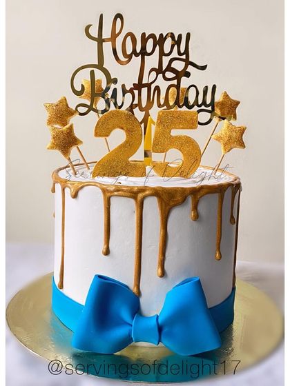 A classic 25th birthday cake with a gold drip and a big blue bow. It's a festive and elegant design for a milestone celebration.