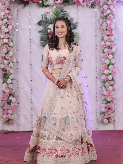 A full-length shot of the bride in her pastel lehenga, looking elegant against a floral backdrop.
