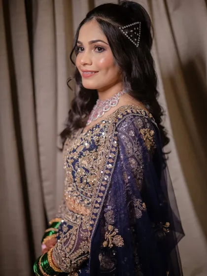 The bride's complete Sangeet look. She wears a stunning navy blue and gold lehenga, with her hair in beautiful curls, ready to hit the dance floor.
