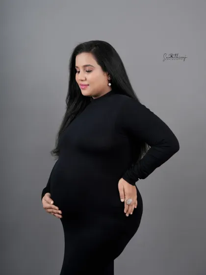 A serene profile shot of a mother-to-be in a black gown. The soft lighting and her gentle expression create a peaceful and elegant portrait.