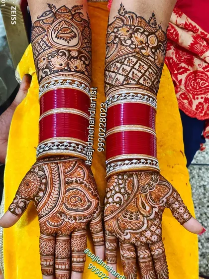 This design shows how my mehandi beautifully complements the traditional bridal choora (bangles). I carefully design the henna to work with the bride's accessories, ensuring a cohesive and elegant look. The patterns here are a mix of paisley and floral motifs.