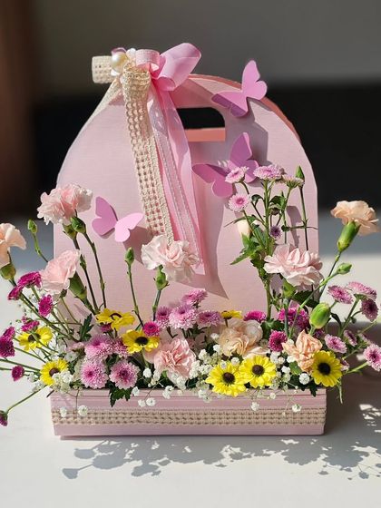 A frontal view of the pink floral caddy, adorned with delicate butterflies and a pearl-trimmed lace ribbon. It’s a sweet and charming way to announce the arrival of a baby girl.