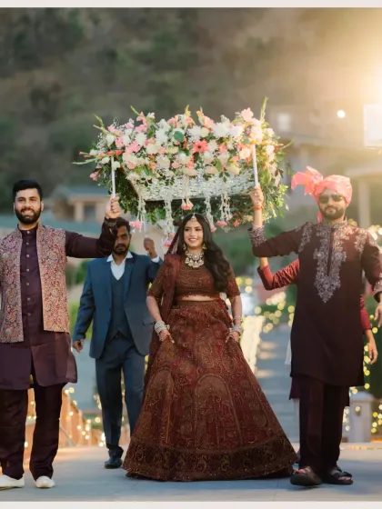 A beautiful shot of the bride's entry, her brothers holding the 'phoolon ki chadar' as she walks with a radiant smile.