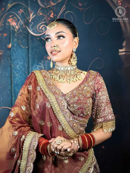 A close-up portrait of a bride with a soft, happy expression. Her makeup includes a shimmery eyelid, a classic winged liner, and a traditional nose ring, capturing the essence of bridal beauty.