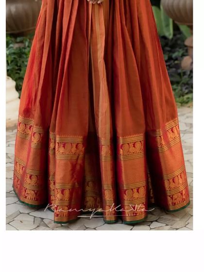 The hem of the rust orange dress highlights the beautiful traditional elephant motifs woven into the silk border.