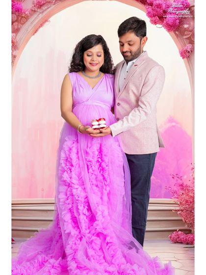 A cute and creative way to celebrate. The couple holds tiny cupcakes, adding a personal and sweet touch to their studio maternity photoshoot.