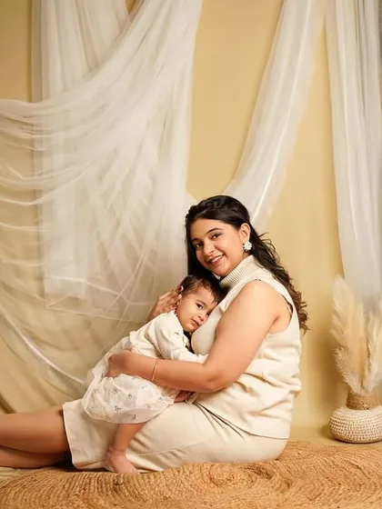 A mother's gentle embrace. This portrait, set against a boho-inspired backdrop with pampas grass and soft fabrics, highlights the tender bond between mother and child.