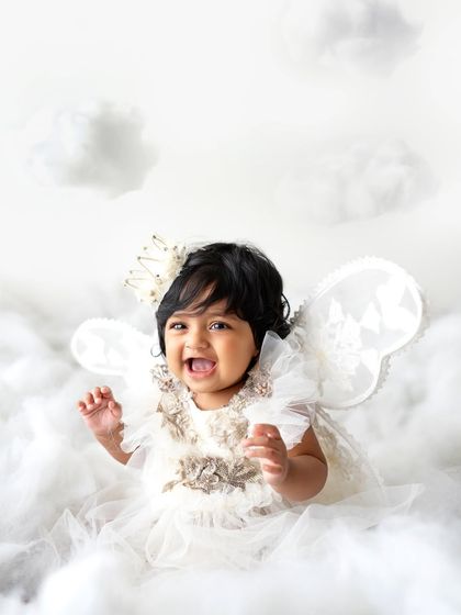 A little angel in the clouds! This theme is so sweet and simple, using a white dress, wings, and a crown to create a heavenly scene.