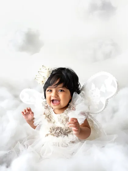 A little angel in the clouds! This theme is so sweet and simple, using a white dress, wings, and a crown to create a heavenly scene.