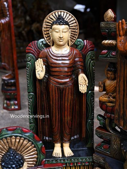A detailed shot of a standing Buddha statue, focusing on the gentle expression and the texture of the painted robes.