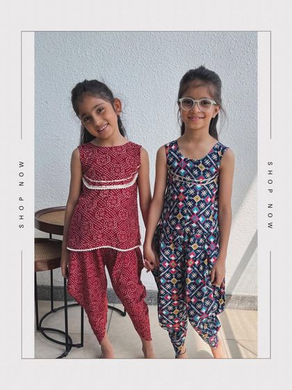 Two friends showing off their traditional dhoti-kurta sets. One is a deep red bandhani print, and the other is a multi-color patola print.