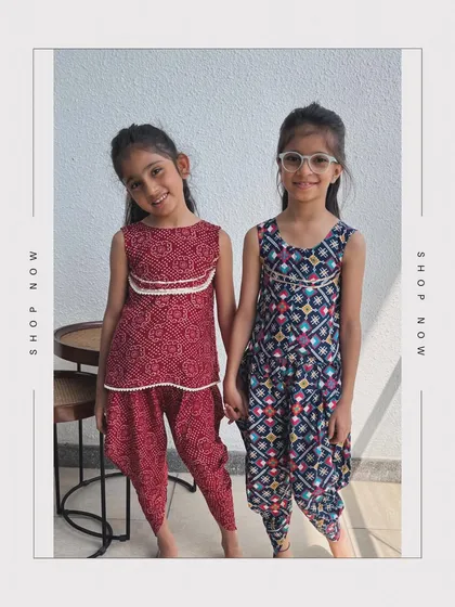 Two friends showing off their traditional dhoti-kurta sets. One is a deep red bandhani print, and the other is a multi-color patola print.