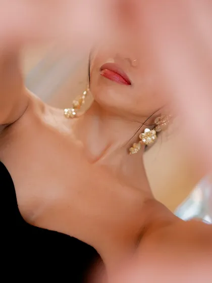 A creative, abstract close-up of a model's face, shot through a blurred foreground. This artistic portrait focuses on color and texture.