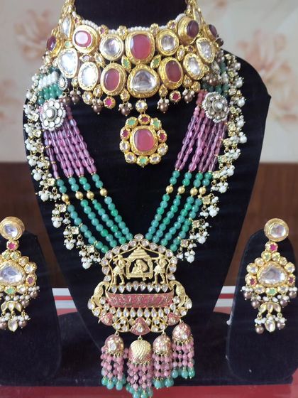 A Sabyasachi-inspired bridal set with a Navratna choker and a long, multi-colored beaded necklace with a temple pendant.