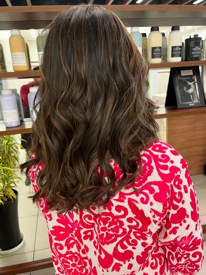 Caramel highlights on a dark brown base, styled into beachy waves. This look is perfect for a touch of brightness.