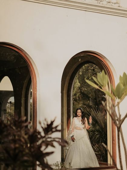 A creative portrait looking through an archway. This composition adds depth and a sense of peeking into a private moment, highlighting the bride's elegance.