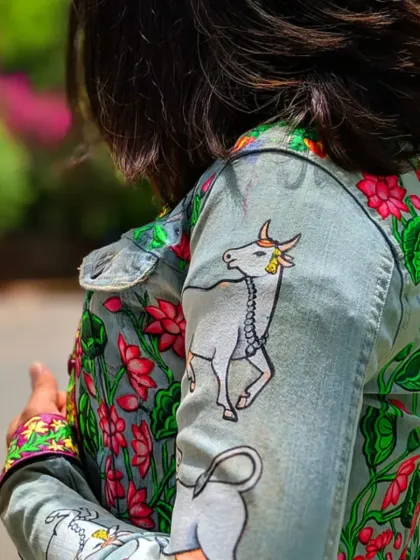 This denim jacket features a hand-painted design inspired by traditional Pichwai art. I depicted the sacred cow, Kamdhenu, surrounded by blooming lotuses, bringing a touch of timeless Indian heritage to modern fashion. The details on the sleeves and cuffs complete the narrative.