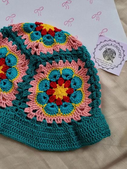 A close-up of the intricate floral granny squares that make up our popular bucket hat. We love how the teal, pink, and yellow colors work together.