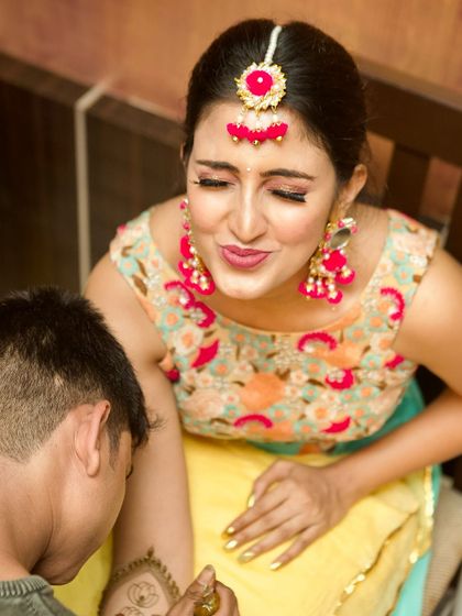 A candid moment from the mehendi ceremony. The bride's makeup is minimal yet radiant, allowing her natural joy and excitement to shine through.