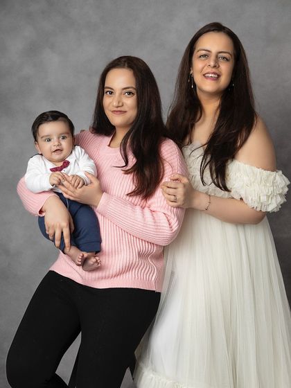 A portrait of two sisters with the family's new baby. This photo celebrates sisterhood and the joy of welcoming a new member to the family.