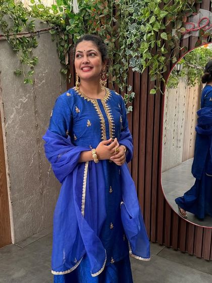 A happy, candid moment of Priyanka Barve in her blue concert outfit, with her reflection captured in the mirror.