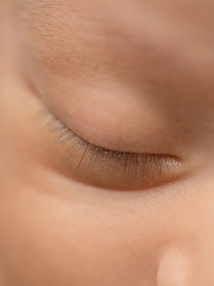 A macro shot of a newborn's delicate eyelashes, showcasing the incredible detail we capture in our sessions.
