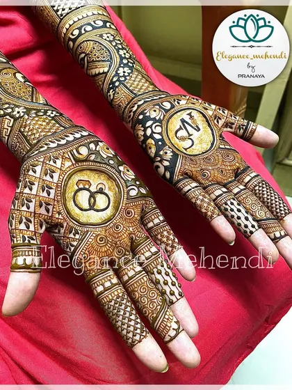 A close-up of a custom engagement mehendi, showing the detail in the couple's initials and the interlocking rings.