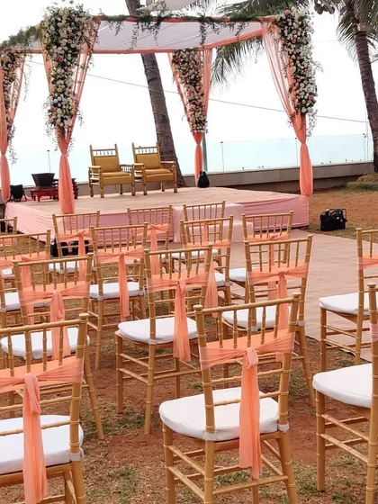 A simple yet elegant mandap setup for a beach wedding. The focus here is on the clean lines and the beautiful view, with peach drapes and white floral accents adding a touch of softness.