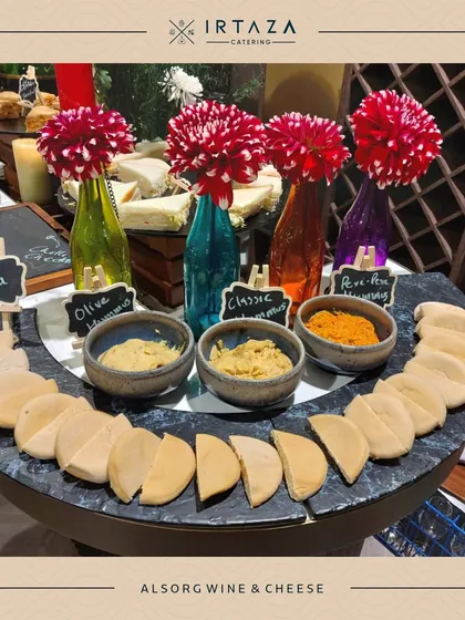 A sophisticated wine and cheese station I set up for my client, ALSORG. The display includes a variety of hummus and pita, with colorful flowers in bottles adding a stylish touch.