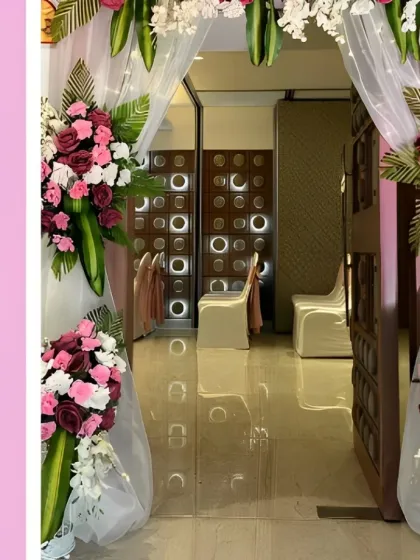 An elegant doorway framed with bouquets of pink and white roses and sheer, sparkling drapes, offering a glimpse into the beautifully decorated event space.