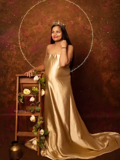 A regal portrait of a mom-to-be in a shimmering golden gown, complete with a crown and a halo of light. This setup creates a divine, goddess-like image celebrating motherhood.