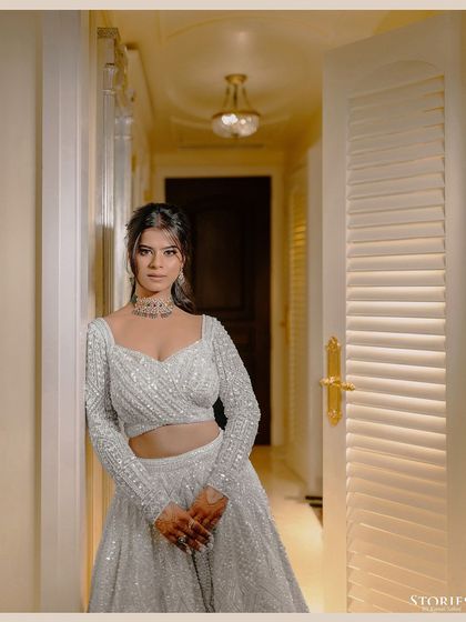 A simple, elegant portrait of the bride, Akanksha, in her white lehenga, standing in a brightly lit corridor.