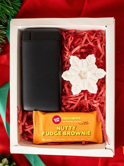 A sleek and simple Christmas gift for a colleague. This box contains a black glasses case, a nutty fudge brownie, and a snowflake-shaped candle, combining utility with a festive touch.