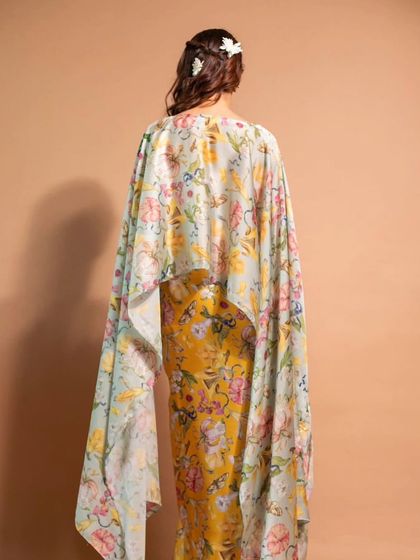 The back view of the floral cape dress, showing the simple yet elegant hairstyle with a small floral accessory.
