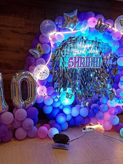 A vibrant butterfly theme in shades of purple and blue for a 10th birthday. The circular shimmer backdrop and neon-lit frame create a stunning, modern look.