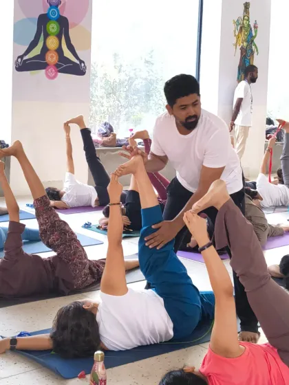 Assisting a student with proper alignment in a supine leg stretch. Our goal is to provide a supportive environment where everyone can deepen their practice safely, regardless of their starting point.