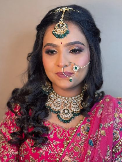 A close-up of a bride in a pink lehenga. Her makeup is soft and natural, with a focus on enhancing her features.