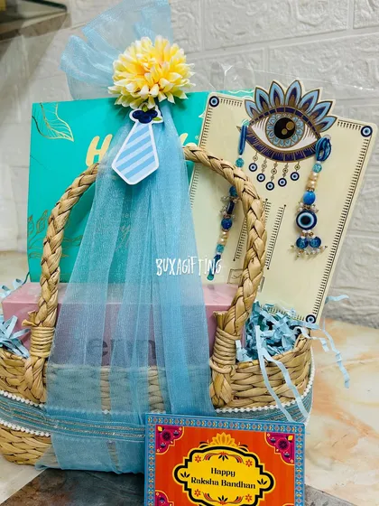 For Raksha Bandhan, I believe in gifting an experience. This premium hamper for a brother and sister-in-law features a beautiful evil eye rakhi set, a makeup kit from Enn Beauty, and a box of dry fruits, all presented in a stylish, handwoven kauna grass basket.