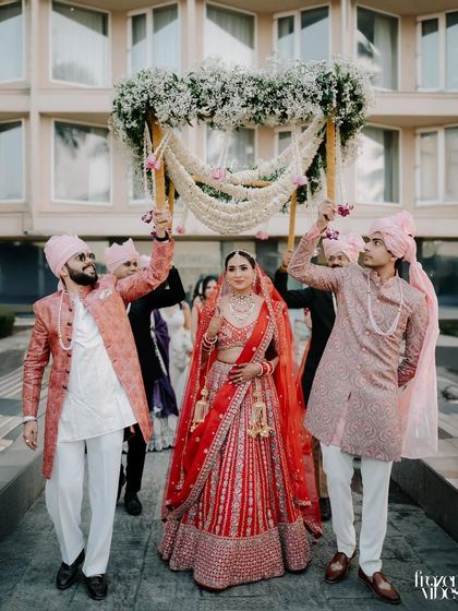 The bride's grand entrance under a beautiful phoolon ki chadar held by her brothers. This is a classic, joyous moment full of family love.