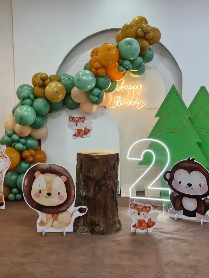 Our modern and cute jungle theme is perfect for a second birthday. This setup features pastel balloons, adorable animal cutouts, a rustic log prop, and a neon 'Happy Birthday' sign.