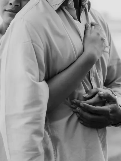A black and white detail shot of a couple's embrace, focusing on the hands and the closeness. This image highlights the comfort and security found in a loving hug.