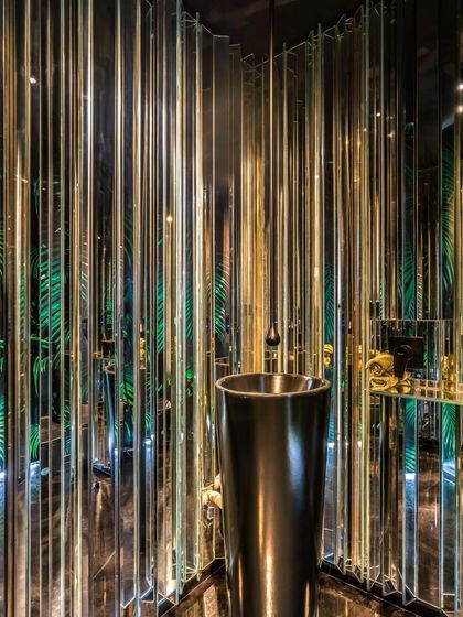 Another view of the Apartment 56 powder room, showing the freestanding black basin and pendant light. The interplay of reflections, light, and pattern creates a dramatic and memorable experience for guests.