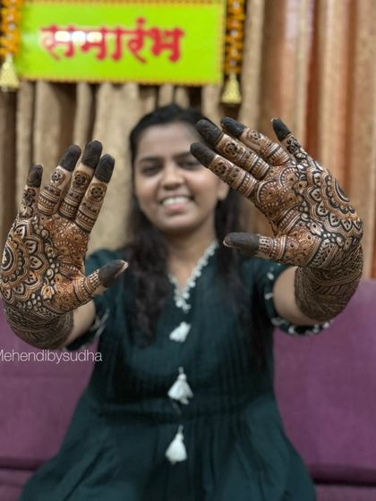 Shreya smiling brightly as she displays both hands, featuring matching mandala and check patterns.